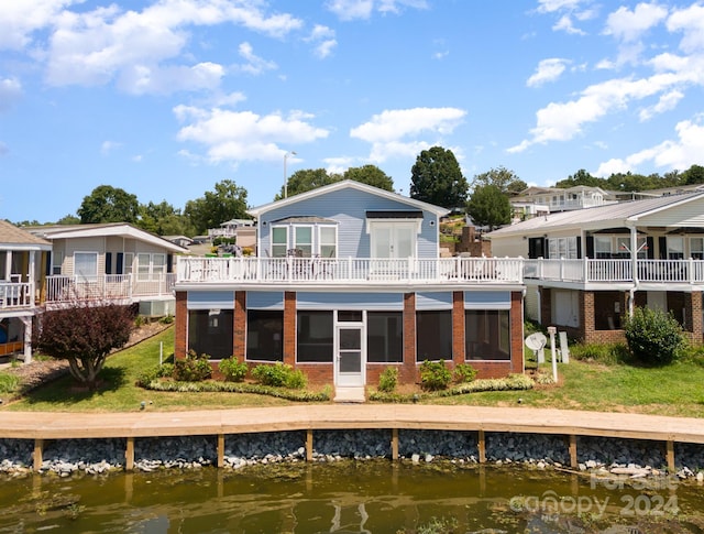 rear view of house with a lawn and a water view