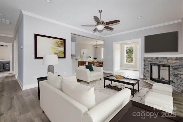 living room with crown molding, a stone fireplace, hardwood / wood-style floors, and ceiling fan