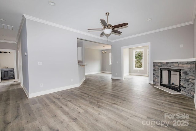 unfurnished living room featuring ornamental molding, a stone fireplace, ceiling fan with notable chandelier, and hardwood / wood-style floors