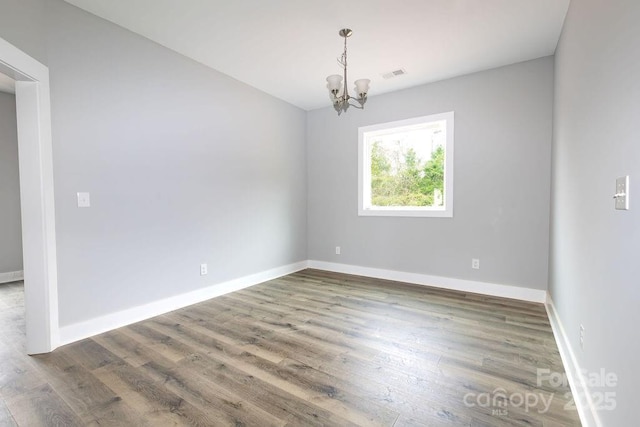 unfurnished room with dark hardwood / wood-style flooring and a chandelier