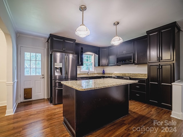 kitchen with light stone counters, a kitchen island, dark hardwood / wood-style floors, stainless steel appliances, and decorative light fixtures