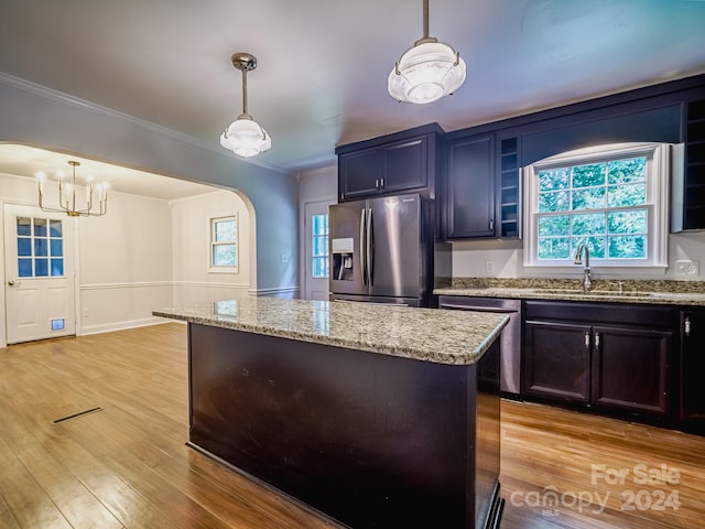 kitchen featuring hanging light fixtures, a kitchen island, appliances with stainless steel finishes, ornamental molding, and light hardwood / wood-style floors