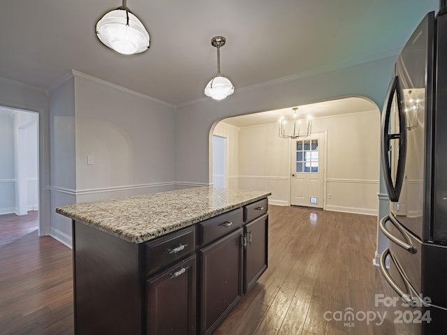 kitchen featuring a kitchen island, dark wood-type flooring, stainless steel fridge, crown molding, and decorative light fixtures