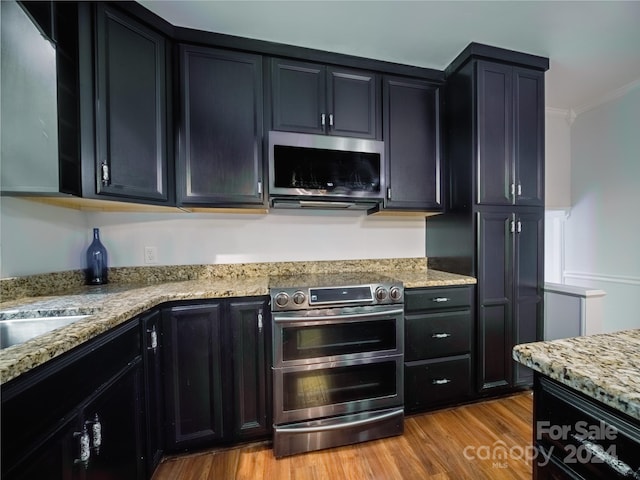 kitchen featuring light stone countertops, crown molding, appliances with stainless steel finishes, and light hardwood / wood-style flooring