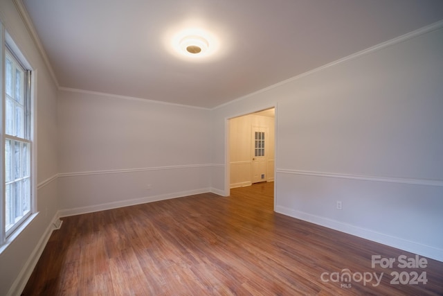 empty room featuring a wealth of natural light, crown molding, and dark hardwood / wood-style flooring