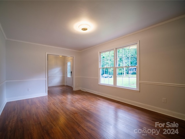 spare room with ornamental molding and dark hardwood / wood-style floors