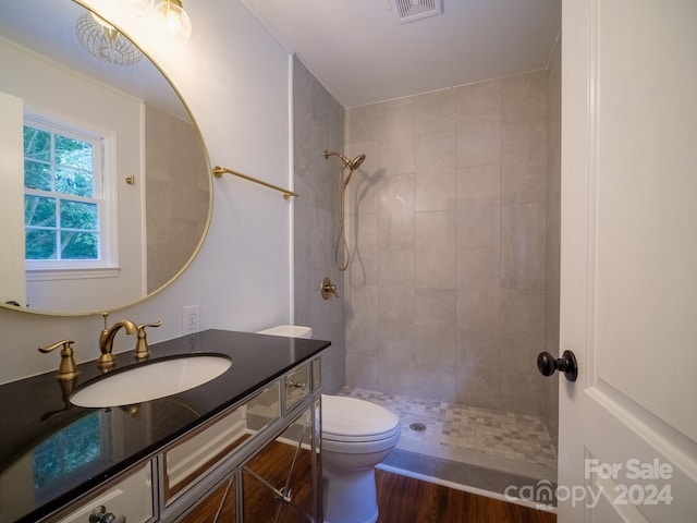 bathroom featuring vanity, toilet, hardwood / wood-style flooring, and tiled shower