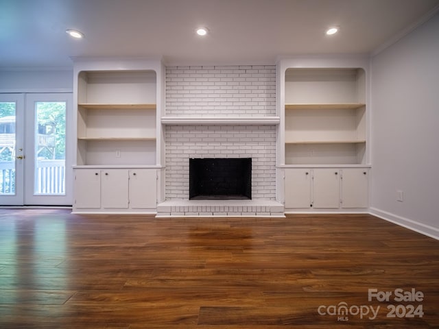 unfurnished living room featuring dark wood-type flooring, a brick fireplace, built in features, and french doors