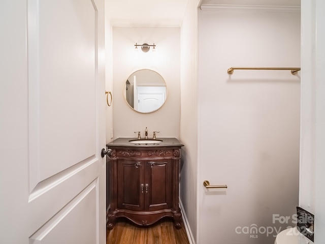 bathroom featuring vanity, ornamental molding, wood-type flooring, and toilet