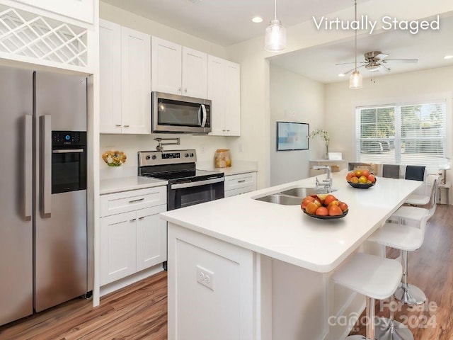 kitchen with a center island with sink, sink, white cabinets, and stainless steel appliances