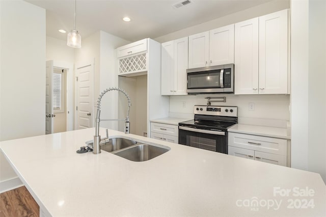 kitchen featuring dark hardwood / wood-style floors, sink, decorative light fixtures, white cabinetry, and appliances with stainless steel finishes