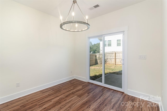 empty room featuring dark wood-type flooring and an inviting chandelier