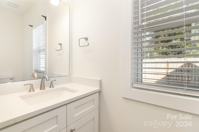 bathroom with a wealth of natural light, vanity, and toilet