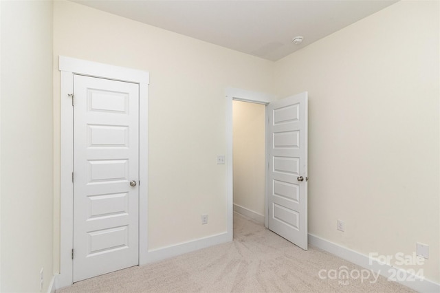 unfurnished bedroom with a closet and light colored carpet