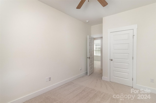 unfurnished bedroom featuring light carpet, a closet, and ceiling fan