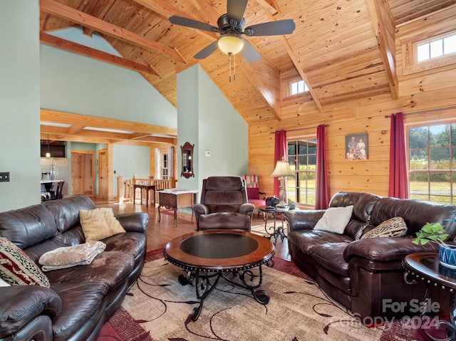 living room with light wood-type flooring, wood walls, beamed ceiling, and plenty of natural light