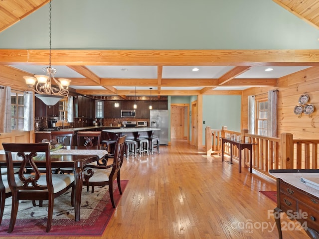 dining area featuring a notable chandelier, light hardwood / wood-style floors, lofted ceiling with beams, and sink