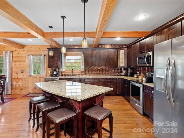 kitchen featuring dark brown cabinetry, stainless steel appliances, light wood-type flooring, and a center island