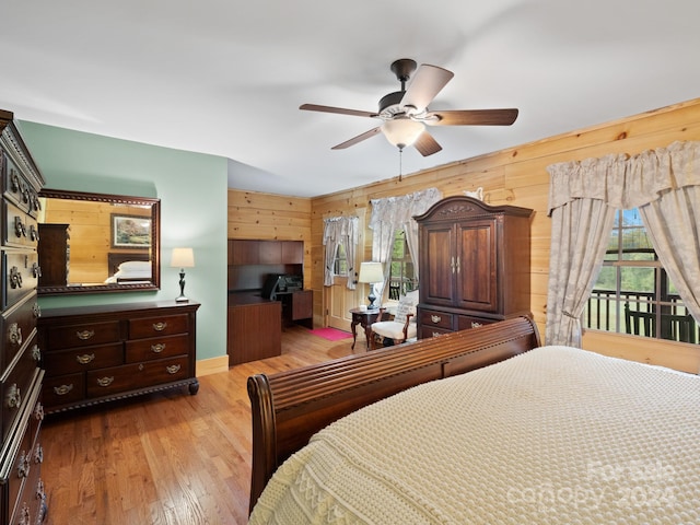 bedroom featuring ceiling fan, wooden walls, light wood-type flooring, and access to outside