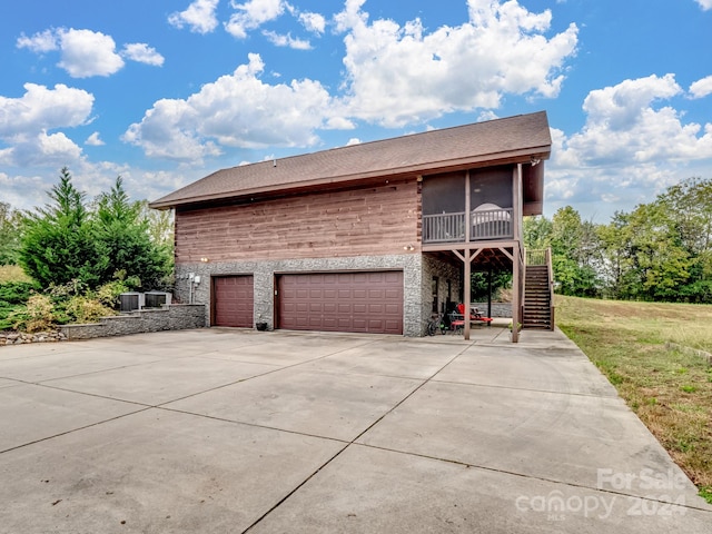 view of front of property featuring central AC unit, a garage, and a sunroom