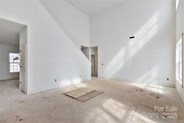 unfurnished living room with a high ceiling and baseboards