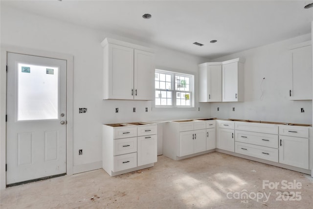 kitchen featuring concrete flooring and white cabinetry