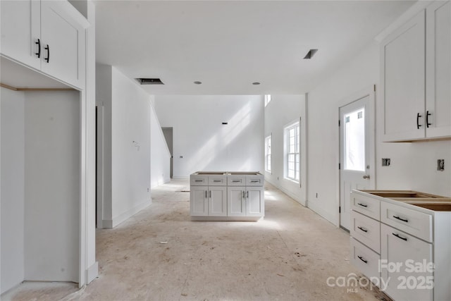 kitchen featuring visible vents, white cabinetry, and baseboards