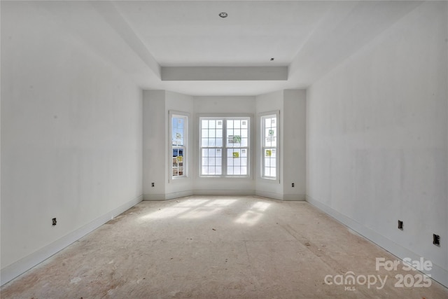 unfurnished room with a raised ceiling and baseboards