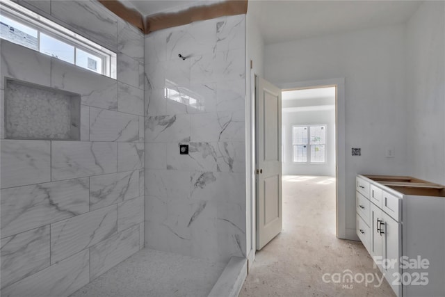 full bath with a healthy amount of sunlight, a tile shower, and vanity