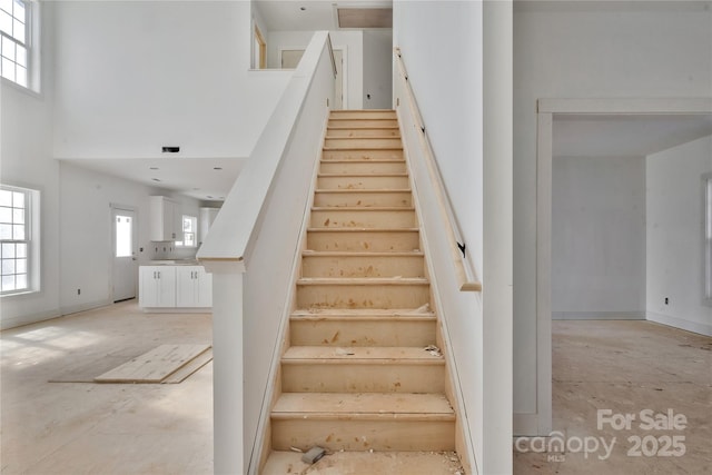 stairway featuring a towering ceiling