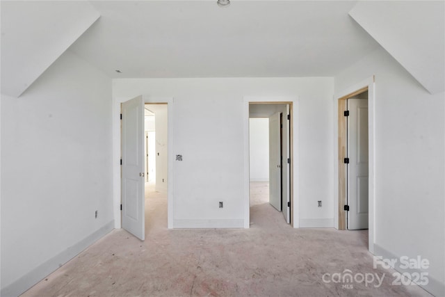 unfurnished bedroom featuring light carpet, baseboards, and lofted ceiling