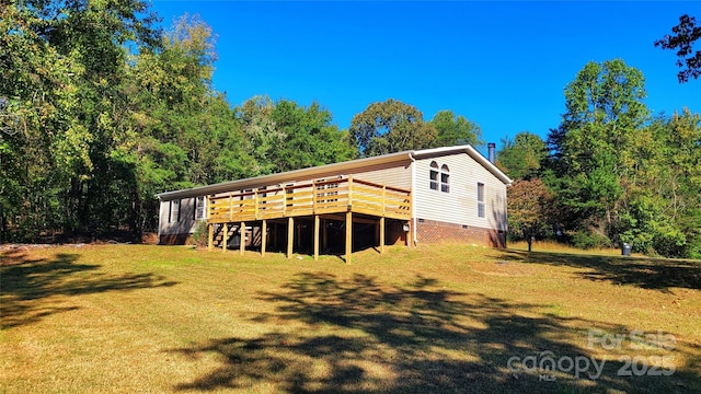 rear view of property featuring a wooden deck and a yard