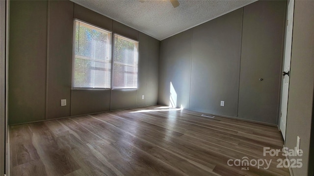 empty room featuring ceiling fan, hardwood / wood-style flooring, vaulted ceiling, and a textured ceiling