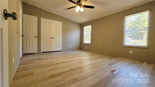 unfurnished bedroom with ceiling fan, lofted ceiling, and light wood-type flooring