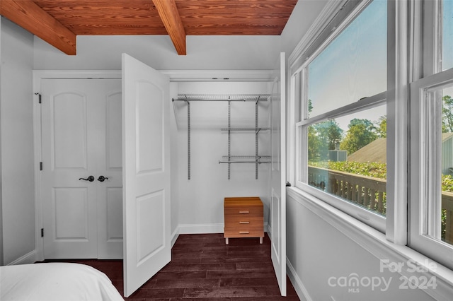 bedroom with beam ceiling, dark hardwood / wood-style flooring, a closet, and wood ceiling