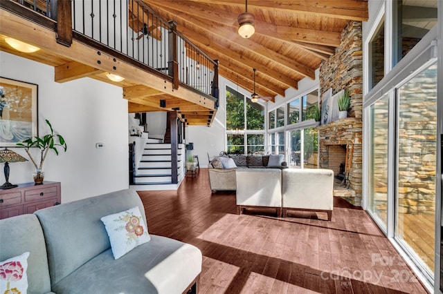 living room with wood ceiling, dark wood-type flooring, high vaulted ceiling, beamed ceiling, and a fireplace