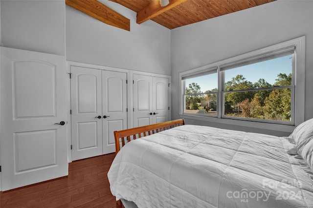 bedroom with multiple closets, beamed ceiling, wood ceiling, and dark hardwood / wood-style floors