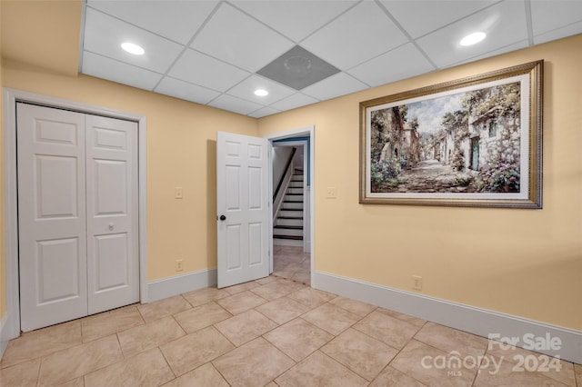 unfurnished bedroom featuring light tile patterned floors, a paneled ceiling, and a closet