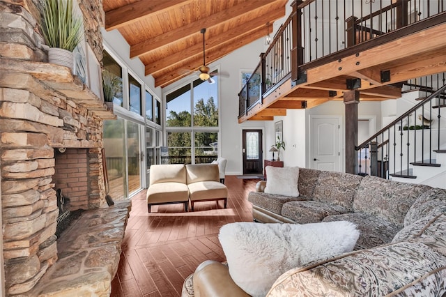 living room featuring high vaulted ceiling, a stone fireplace, ceiling fan, beam ceiling, and wood-type flooring