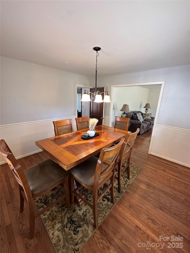 dining space featuring dark wood-type flooring and a chandelier