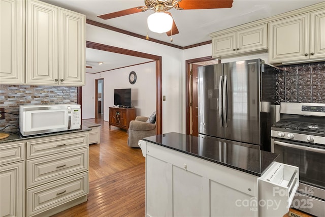 kitchen with stainless steel appliances, cream cabinets, ornamental molding, decorative backsplash, and light wood-type flooring