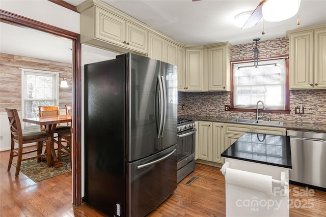 kitchen with decorative light fixtures, appliances with stainless steel finishes, sink, and cream cabinetry