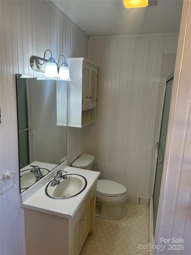 bathroom featuring tile patterned flooring, vanity, an enclosed shower, and toilet