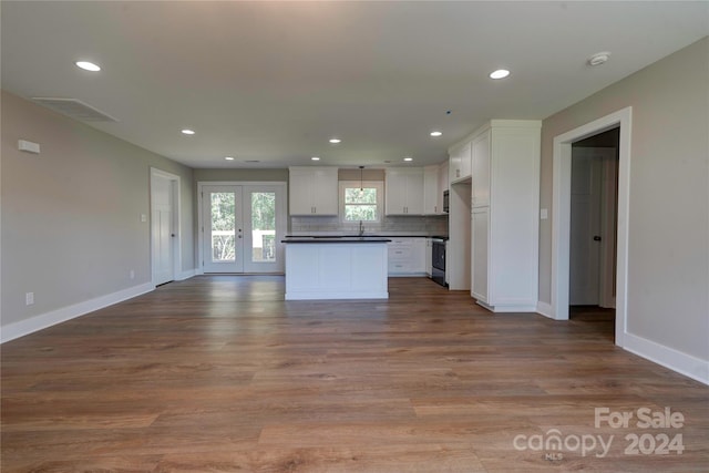 kitchen with decorative backsplash, white cabinetry, a kitchen island, light wood-type flooring, and sink