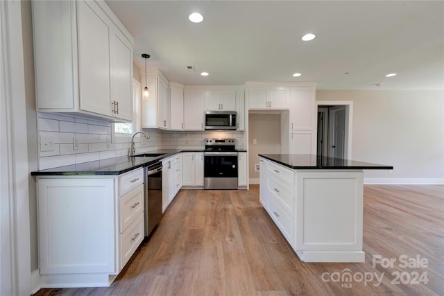 kitchen with white cabinets, pendant lighting, sink, light hardwood / wood-style flooring, and stainless steel appliances