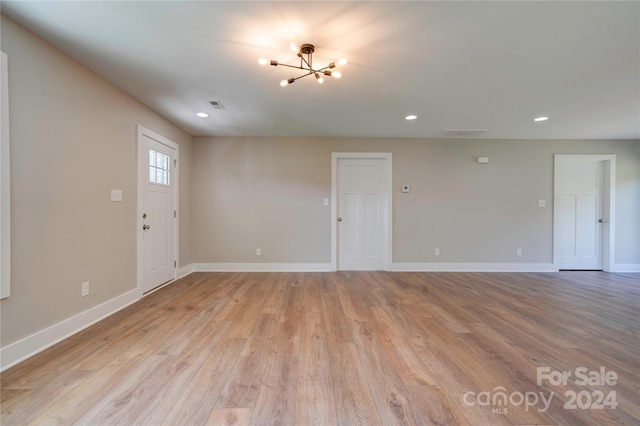 spare room with light hardwood / wood-style flooring and a chandelier