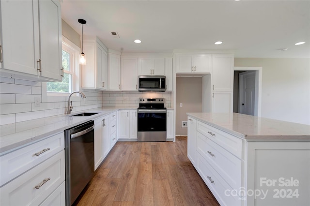 kitchen with pendant lighting, sink, light hardwood / wood-style flooring, white cabinetry, and appliances with stainless steel finishes