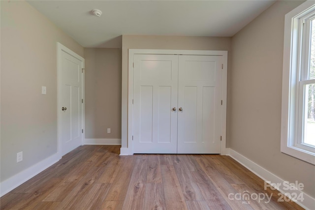 unfurnished bedroom featuring light wood-type flooring and a closet