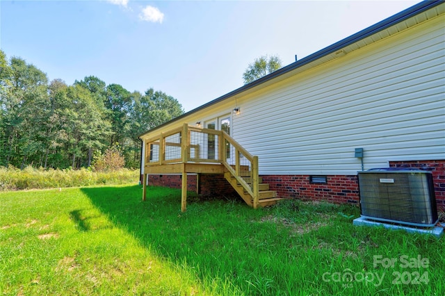 rear view of property featuring a wooden deck, a yard, and central AC