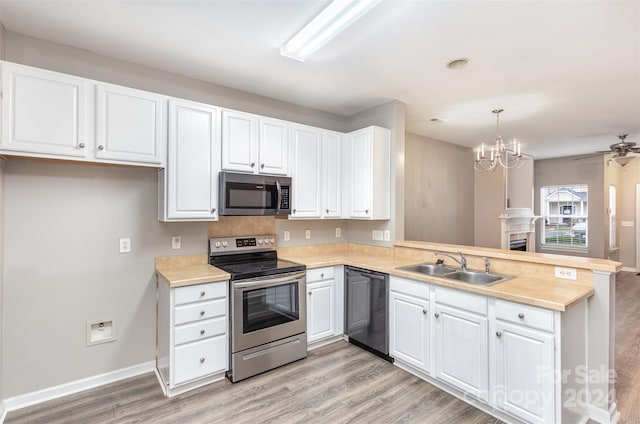 kitchen featuring appliances with stainless steel finishes, white cabinetry, light hardwood / wood-style flooring, decorative light fixtures, and sink